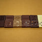 Various chocolate squares engraved with Bogolan symbols.